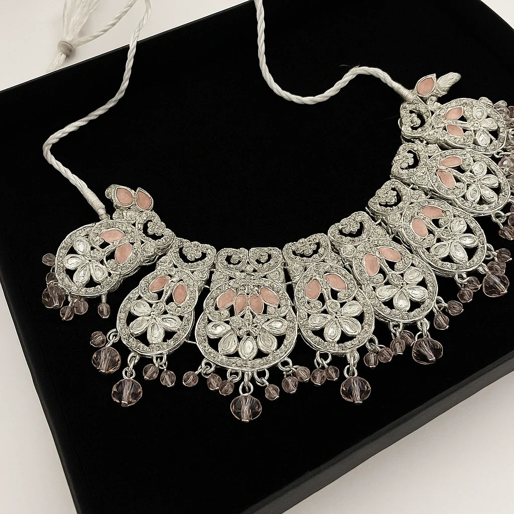 Decorative silver necklace with pink stones on a black surface