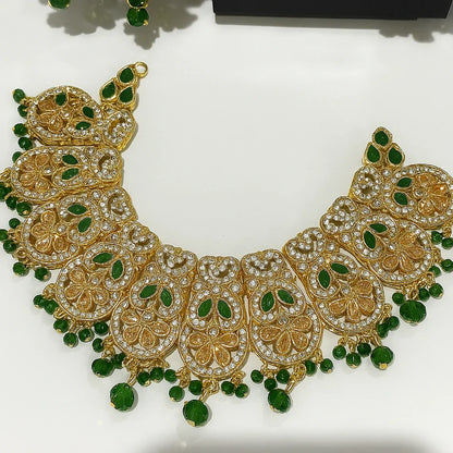 Gold necklace with green gemstones on a white background
