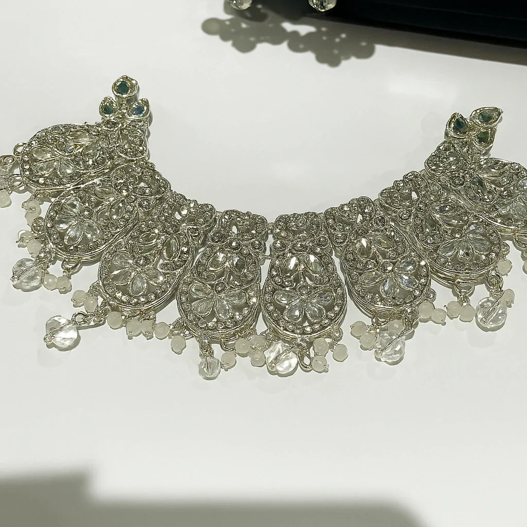 Silver necklace with intricate designs and beads on a white background