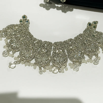 Silver necklace with intricate designs and beads on a white background