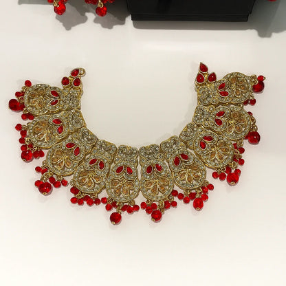 Ornate gold necklace with red beads on a white background