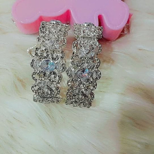 Silver earrings with gemstones on a pink floral cushion